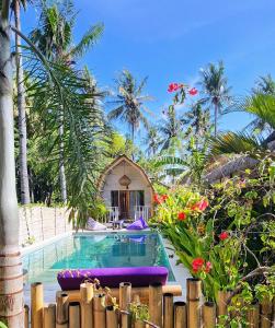 a swimming pool in front of a house with palm trees at Purple Beach - Maïthélia - Gili Air in Gili Air