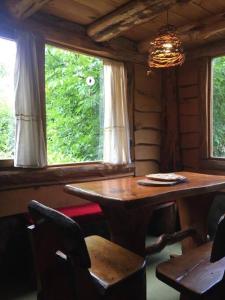 comedor con mesa, sillas y ventana en Cabaña Mirador del Valle en Lago Puelo
