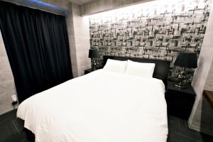 1 dormitorio con cama blanca y pared de ladrillo en Regalo芝浦 501, en Tokio