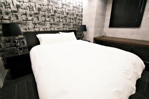 1 cama blanca grande en un dormitorio con pared en Regalo芝浦 501 en Tokio