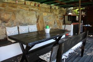 een houten tafel met kussens op een bank naast een stenen muur bij Miranta in Nikiti