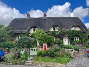 a thatched house with a garden in front of it at Pear Tree Loft in Lacock