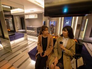 Due donne sedute in una stanza con un cellulare di HOTEL U's Kouroen - Vacation STAY 11230v a Nishinomiya