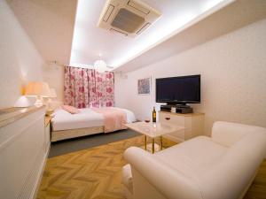 HOTEL U's Kouroen - Vacation STAY 11243v في نيشينومايا: غرفة بسريرين وتلفزيون وأريكة
