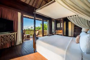 a bedroom with a bed and a balcony with a television at HOMM Saranam Baturiti, Bali in Bedugul