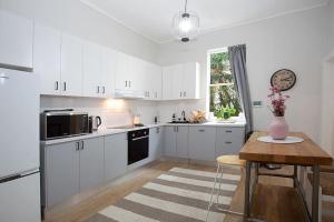 a kitchen with white cabinets and a table with a vase of flowers at Large 4 Bed Beachside Haven 50m to Bondi Beach in Sydney