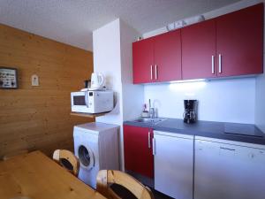 a small kitchen with red cabinets and a washing machine at Appartement Auris, 4 pièces, 8 personnes - FR-1-297-46 in Auris