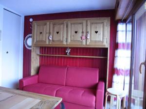 a living room with a pink couch and wooden cabinets at Studio cabine 3 couchages au pied des pistes, ascenseur, casiers à ski, parking - Auris en Oisans - FR-1-297-76 in Auris