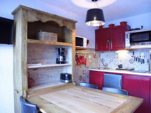 a kitchen with a wooden table and red cabinets at Studio cabine 3 couchages au pied des pistes, ascenseur, casiers à ski, parking - Auris en Oisans - FR-1-297-76 in Auris