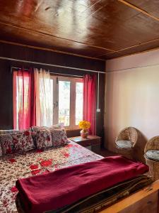 a bedroom with a large bed with red curtains at Dilpali Home Cum Farm stay in Sukhia Pokhari