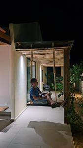 a young man sitting on a porch swing at Moon homestay Phu Yen in Phú Lac