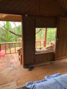 a room with a view of a porch with a bed and a deck at Tetebatu Sama Sama Bungalows in Tetebatu