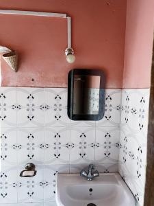 a bathroom with a sink and a tv on the wall at Dilpali Home Cum Farm stay in Sukhia Pokhari