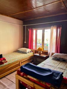 a bedroom with two beds and a window at Dilpali Home Cum Farm stay in Sukhia Pokhari