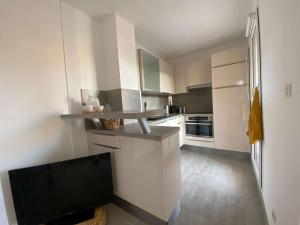 een keuken met witte kasten en een flatscreen-tv bij Appartement Cavalière, 3 pièces, 5 personnes - FR-1-308-137 in Le Lavandou