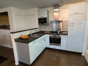 a kitchen with white cabinets and a bowl of fruit on the counter at Walensee Apartment, Lake & Alpine Dream in Unterterzen