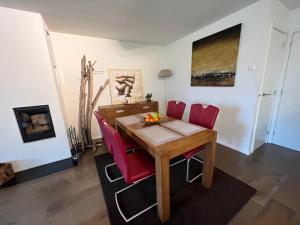 a dining room with a wooden table and red chairs at Walensee Apartment, Lake & Alpine Dream in Unterterzen