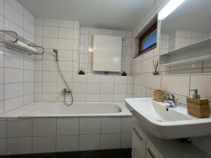 a white bathroom with a tub and a sink at Walensee Apartment, Lakeside Dream in Unterterzen