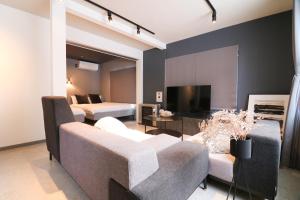 a living room with two beds and a couch and a tv at Guest house SUMIKAWA in Sapporo