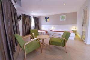 um quarto de hotel com duas camas e uma mesa e cadeiras em Hotel Pintar em Parit Raja