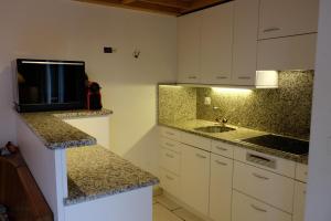a kitchen with white cabinets and a tv on a counter at Arca 12 in Leukerbad