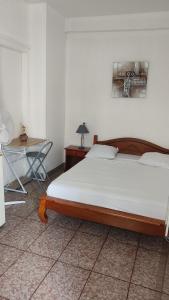 a bedroom with a large bed and a table at Hôtel Le Nathania in Saint-Pierre