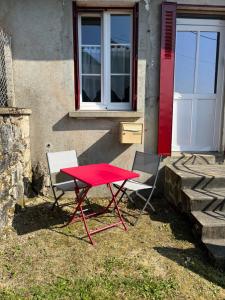 czerwony stół i dwa krzesła przed budynkiem w obiekcie Maison au coeur du Morvan w mieście Arleuf +2 zdjęcia