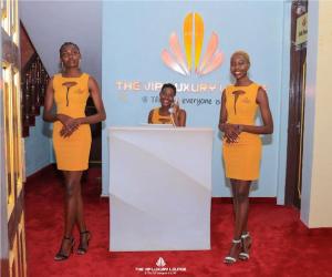 Trois femmes en robes orange debout derrière un podium dans l'établissement The VIP Luxury Lounge Hotel, à Kisumu