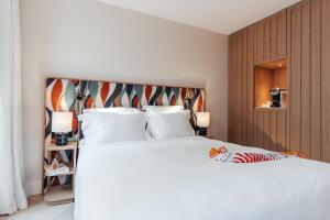 a bedroom with a large white bed with a headboard at Padam Hôtel in Paris