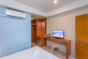 a bedroom with a bed and a desk with a television at Lightplus Khao Lak in Khao Lak