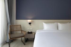 uma cama e uma cadeira num quarto de hotel em Centara Life Cha-Am Beach Resort Hua Hin em Cha Am