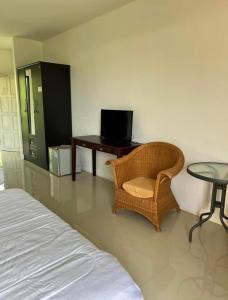 um quarto com uma cama, uma cadeira e uma mesa em Relaxation guesthouse em Thalang