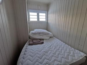 a small white room with a bed with a window at Tangen - cabin with 4 bedrooms - great nature in Norheimsund