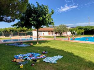 a group of people laying on the grass near a swimming pool at Casa en la Valleta in Ginestar