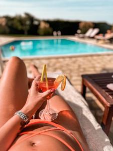 a woman is holding a drink in front of a pool at Beachfront Villa Victoras - With private beach in Sidari