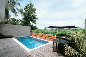 a table with an umbrella next to a swimming pool at The Lavana River Villas Lombok in Senggigi