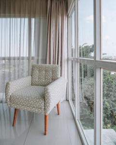 a chair sitting in a room with windows at Horison Inn Antawirya Semarang in Jatingaleh