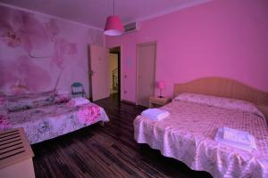 una camera con due letti in una camera rosa di Casa Margherita a Sellia Marina