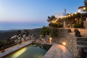 a swimming pool with a view of a mountain at night at Kea Village Suites & Villas in Ioulis