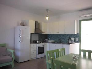 een keuken met een witte koelkast en een tafel en stoelen bij St George Antiparos Apartments and studios in Agios Georgios