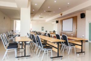 una sala de conferencias con mesas y sillas de madera en Horison Inn Antawirya Semarang, en Jatingaleh