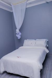 una camera con letto bianco con tenda di The VIP Luxury Lounge Hotel a Kisumu