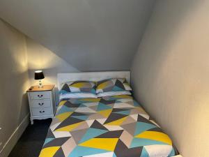 ein kleines Schlafzimmer mit einem Bett und einem Nachttisch in der Unterkunft Rural Chapel Cottage near airport bar & hot tub in Aberdeen