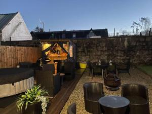 a patio with chairs and tables and a stone wall at Rural Chapel Cottage near airport bar & hot tub in Aberdeen