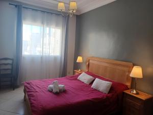 ein Teddybär auf einem roten Bett in der Unterkunft Grand appartement calme et lumineux + Parking GRATUIT in Casablanca