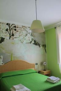 una camera con un letto verde e un dipinto sul muro di Casa Margherita a Sellia Marina