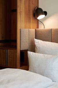 a bedroom with a bed with white sheets and a lamp at Cocoon Sendlinger Tor in Munich