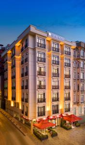 Aspera Hotel Golden Horn في إسطنبول: مبنى كبير فيه مظلات حمراء أمامه