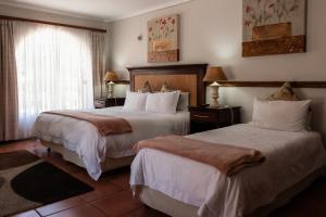 a hotel room with two beds and a window at Park Living Guesthouse in Bloemfontein