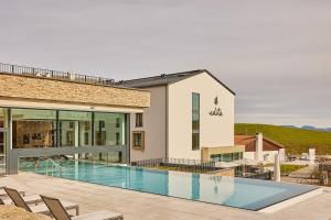 a swimming pool in front of a building at Hotel Edita in Scheidegg